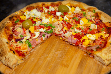Traditional Portuguese pizza with ham, eggs, peppers, hearts of palm, tomatoes, onions, peas and cheese