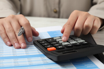 Woman making calculations on calculator at table, closeup