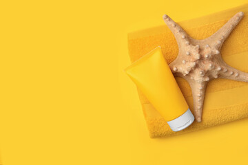 Tube of sunscreen, starfish and towel on orange background, top view with space for text. Sun protection