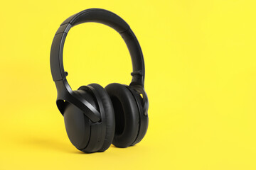 Modern wireless headphones on color background. Space for text
