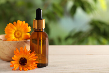 Bottle of essential oil and beautiful calendula flowers on white wooden table outdoors, closeup...