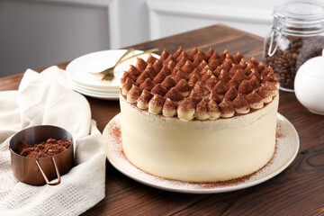 Delicious tiramisu cake with cocoa powder on wooden table