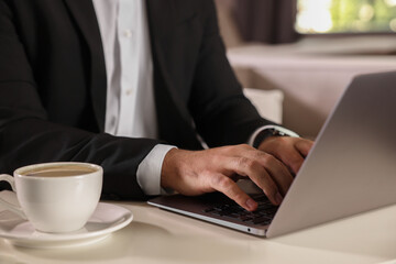 Man working on laptop at table in office, closeup