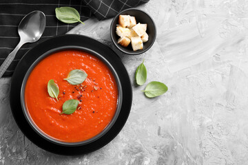 Delicious tomato cream soup served on grey textured table, flat lay. Space for text