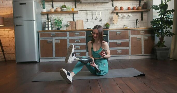 Young woman with disability sits on mat to relax after training