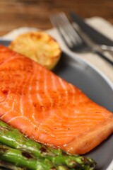 Tasty grilled salmon with asparagus and lemon served on plate, closeup