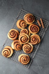 Tasty cinnamon rolls on black table, top view