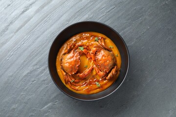 Delicious boiled crabs with sauce in bowl on grey textured table, top view