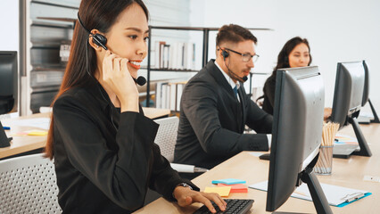 Fototapeta na wymiar Business people wearing headset working in office to support remote customer or colleague. Call center, telemarketing, customer support agent provide service on telephone video conference call. Jivy