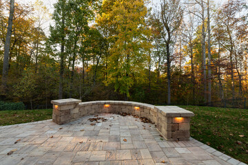 Picturesque backyard view in autumn season with patio pavers and stone wall, autumn leaves, and...