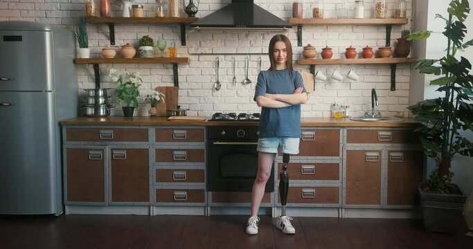 Lady with prosthetic limb stands in kitchen with crossed arms