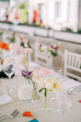 Flowers stand in glasses on a laid festive table