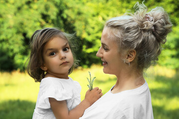 Happy mother with her cute daughter spending time together outdoors