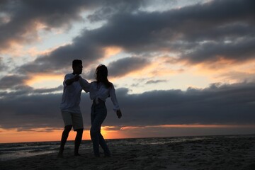 Happy couple dancing on beach at sunset