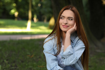 Obraz premium Portrait of beautiful young woman with red hair outdoors. Space for text. Attractive lady posing for camera