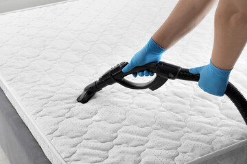 Woman disinfecting mattress with vacuum cleaner, closeup - obrazy, fototapety, plakaty