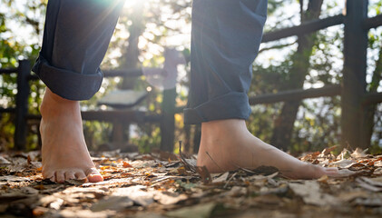 A man walking barefoot on a fallen leafy road. Healthy lifestyle concept
