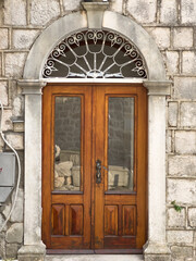 Fototapeta na wymiar Arched wooden front door in an old stone building