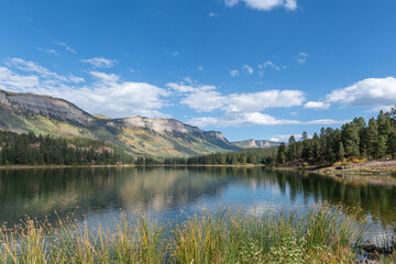 A peaceful lake with the San Juan Mountains and blue sky reflected in its surface near Durango, Colorado.