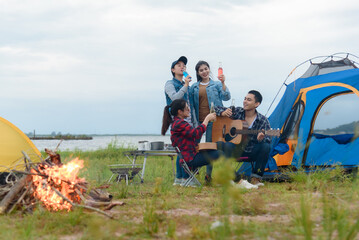Group of Asian friends camping, relaxing by the sea, mountains Have fun drinking alcohol, partying and singing.