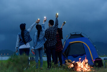 Group of camping friends Lift the glass bottle and cheerfully Camping by the lake