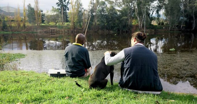 Fishing, friends and men with dog at a lake rear view, bond and fun with conversation in nature. Forest, break and back of fisher people chilling with pet at a river bank talking or waiting for fish
