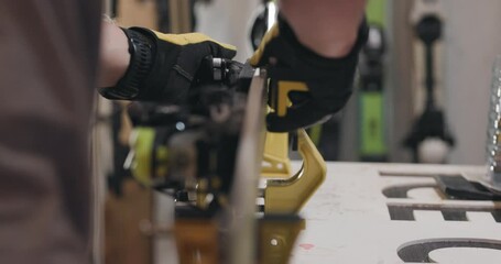 Man servicing skis. Abstract male hands working with special equipment on the ski edge. Close up video recorded with cinema camera.