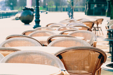 empty tables and chairs in a city street restaurant early in the morning