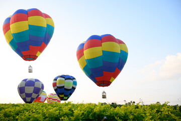 Colorful hot air balloons flying over green tree on blue sky background in nation park.Hot air balloon festival travel concept.