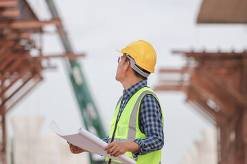 Engineer man with blueprint checking project at construction site, Foreman worker holding plan in building site