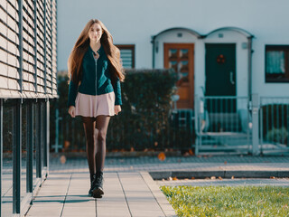 a young woman in a short skirt, black tights and long hair walks along glass display cases; ​