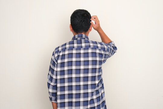 Back view of a man scratching his head showing confuse expression