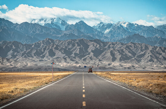 The view of a straight highway going towards the snow capped mountains in regional area in Xinjiang