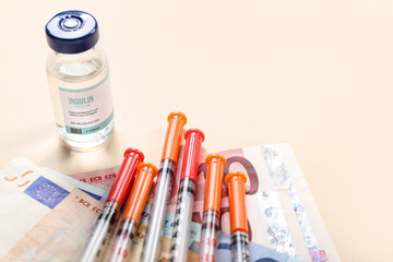 Insulin with syringes and money on beige background, closeup. Expensive medicine concept