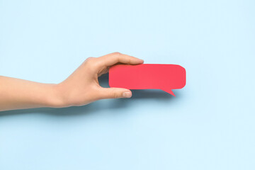 Woman holding blank speech bubble on blue background