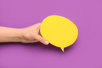 Woman holding blank speech bubble on purple background