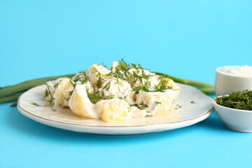 Plate of tasty Potato Salad with greens on blue background