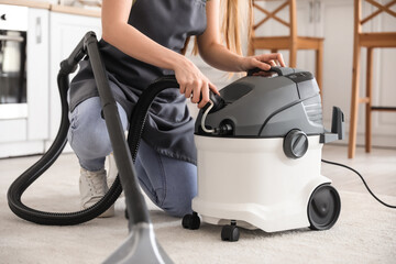 Fototapeta na wymiar Young woman with vacuum cleaner in kitchen, closeup