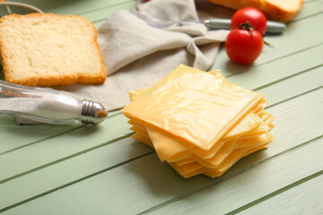 Slices of tasty processed cheese on green wooden background