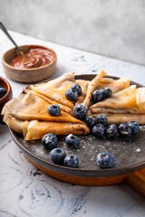 Thin pancakes with chocolate spread and blueberries on the table vertical photo
