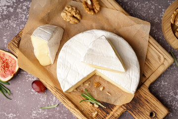 Wooden board with tasty Camembert cheese on grey background