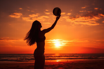 silhouette of young woman playing volleyball on the beach at sunset