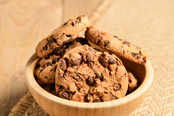 Bowl of tasty cookies with chocolate chips on wooden background