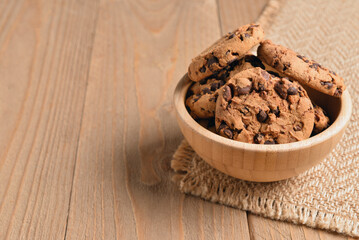 Bowl of tasty cookies with chocolate chips on wooden background