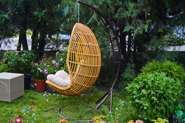 A wicker hanging chair stands in the garden.