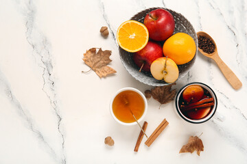Cup of hot mulled wine with orange and bowl of honey on white background