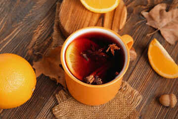 Cup of hot mulled wine with orange and cinnamon on wooden background