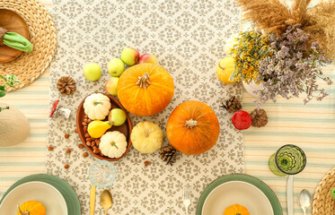 Fototapeta na wymiar Autumn setting with pumpkins and flowers on dining table in room, top view