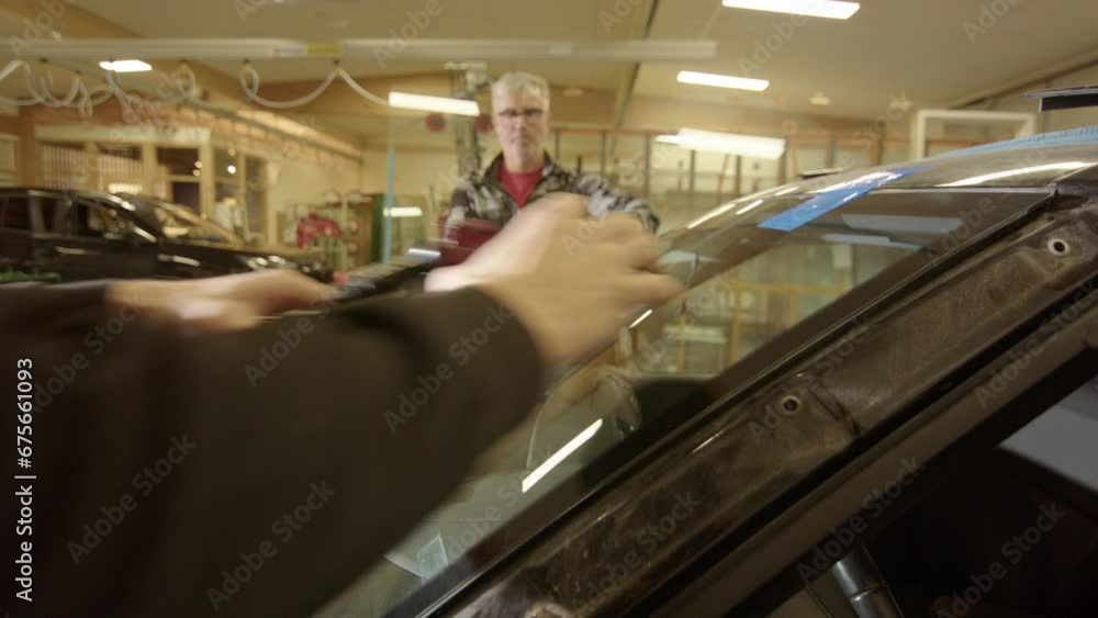 Poster technicians at workshop remove suction cups from windshield after replacement
