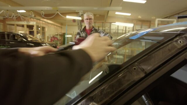 Technicians at workshop remove suction cups from windshield after replacement